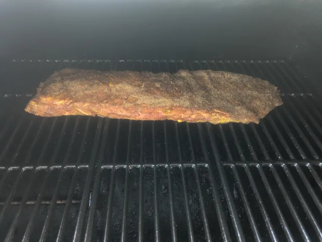 Freshly seasoned St. Louis ribs on the smoker grate